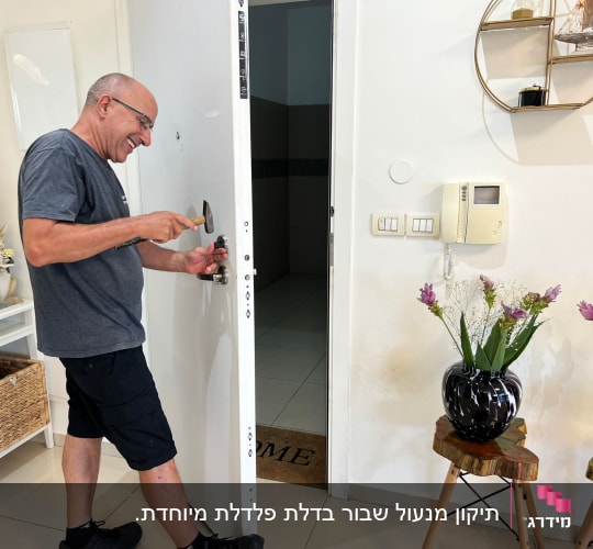 אדם מתקן מנעול דלת עם פטיש